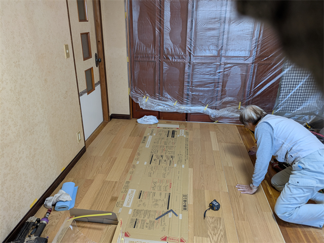 接着剤の塗布範囲を明確にするため床に線を引く職人