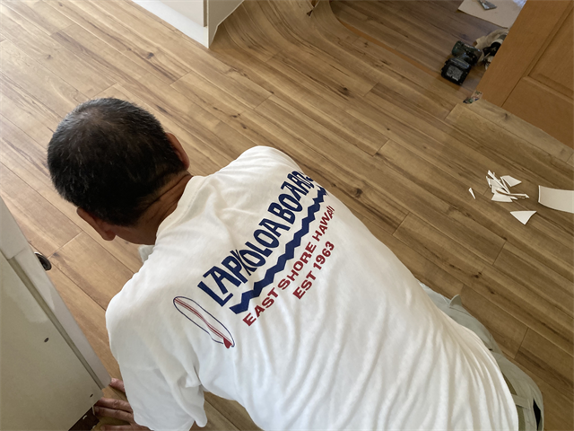 キッチンの床に新設したクッションフロアをなじませる職人