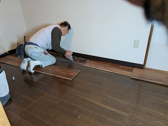 フローリング増し張りのため既存の床に接着剤を塗布する職人