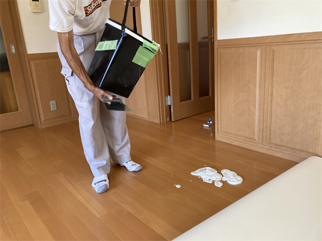 クッションフロア敷設のために接着剤を塗布する職人