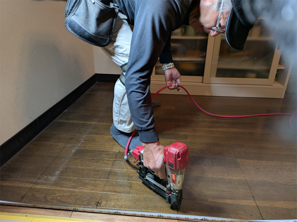 釘打ち機で既存の床に新設フロアに固定する職人