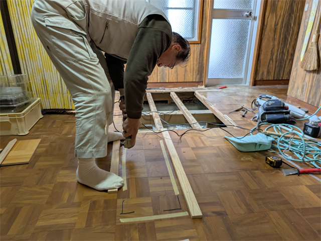 劣化箇所の床をカッターであける職人