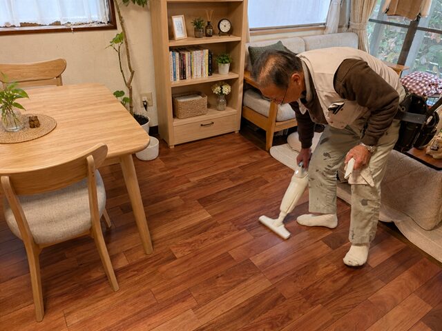 完工後フローリングに掃除機をかける職人